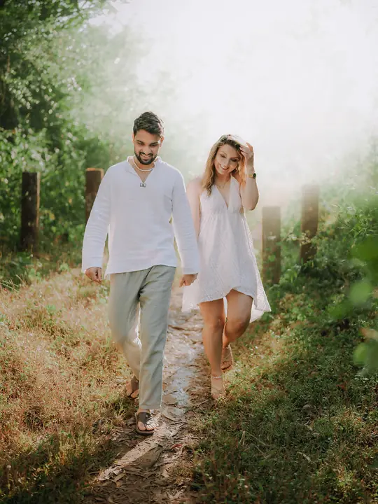 Pratik and Andra walking together through a green woodland in their pre-wedding session.