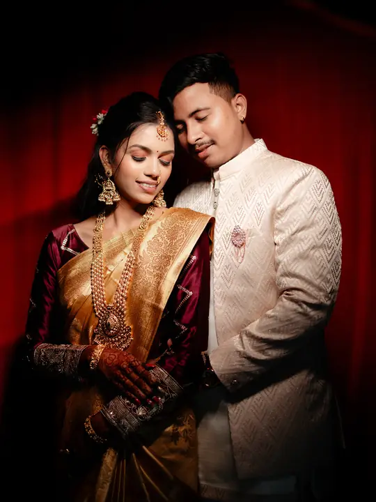 Pritesh and Kaveri in a warmly lit engagement portrait against a deep red backdrop.