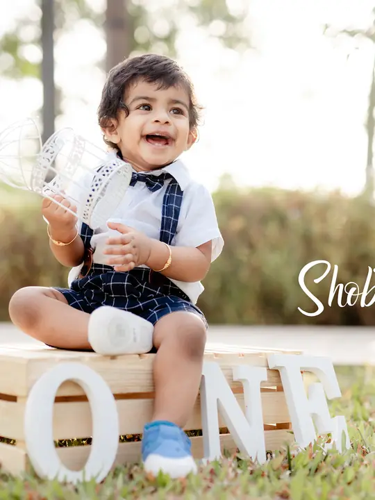 Shobhit smiles in an outdoor portrait celebrating his first birthday.